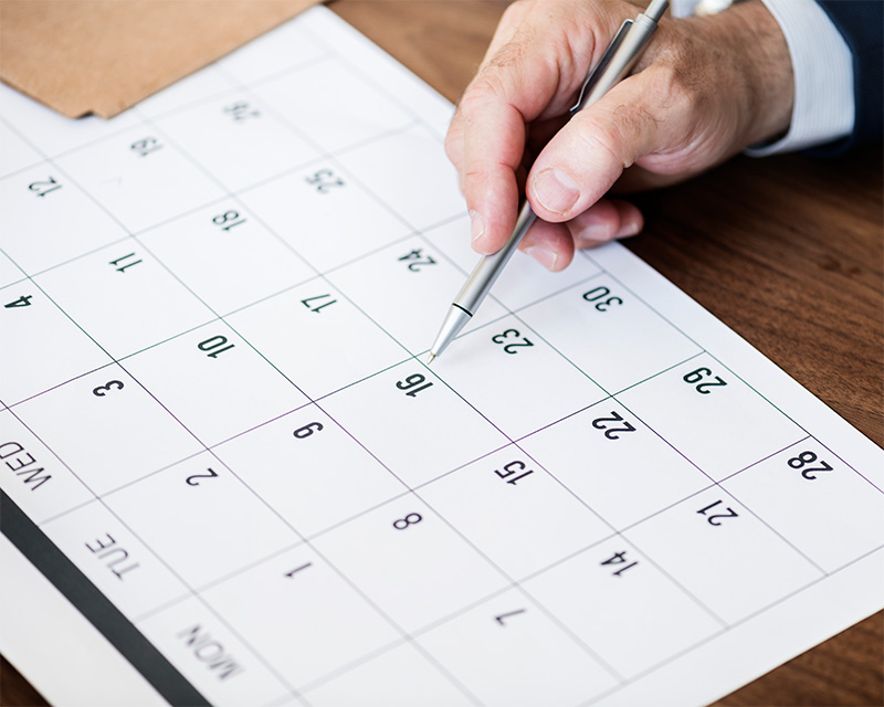 Calendario in cui viene indicato un giorno preciso da una penna tenuta in mano da una persona